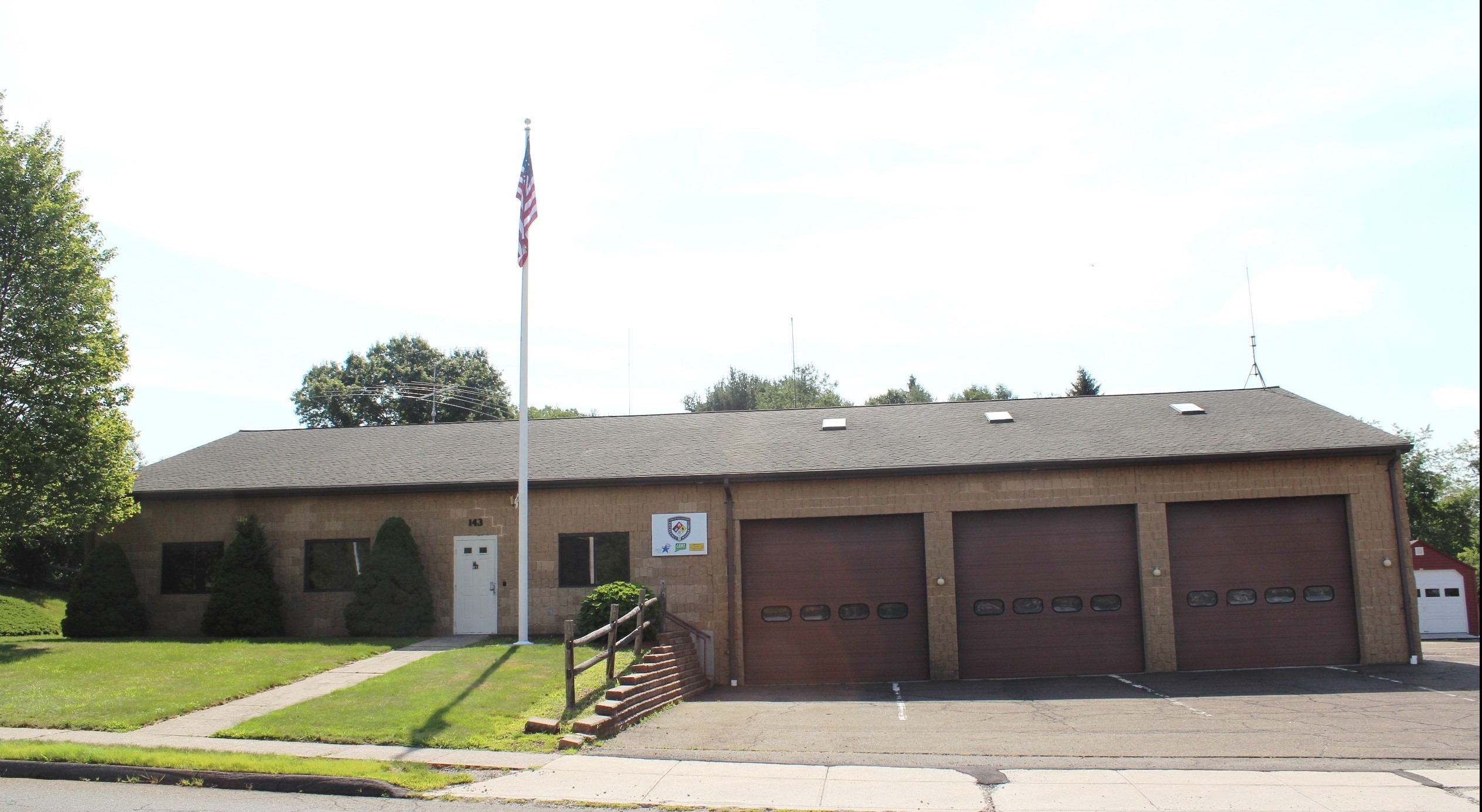 Front of the firehouse with a flagpole and two firetruck bays.